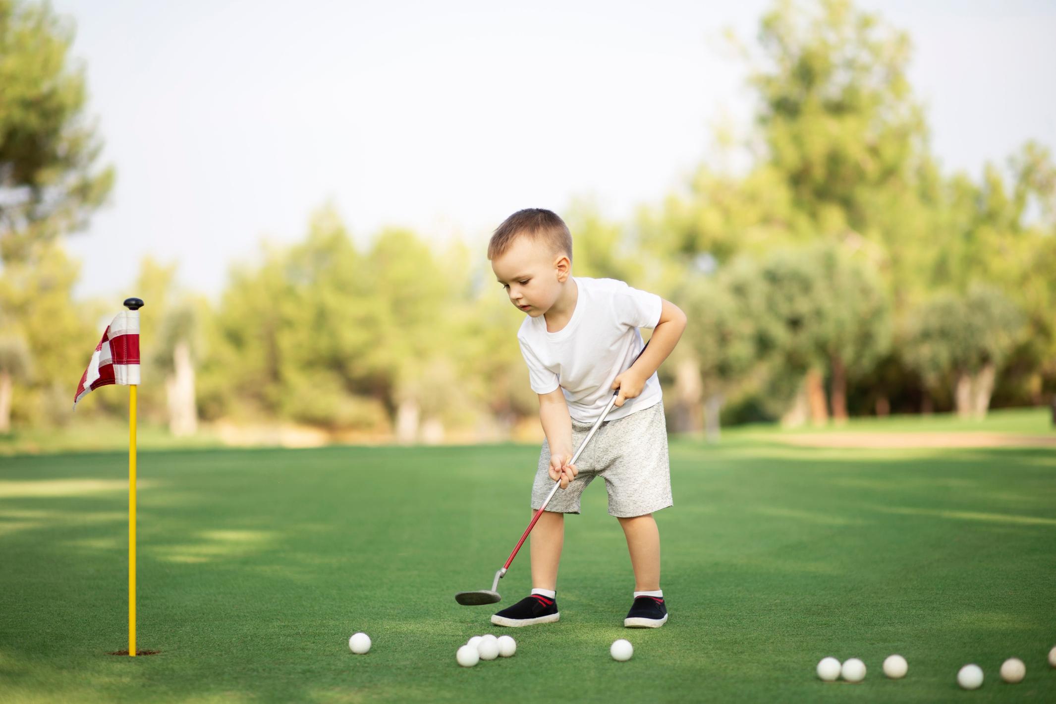 little-boy-playing-golf-with-golf-club-on-green-fi-2023-11-27-05-34-35-utc.jpg